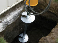 Installing a helical pier system in the earth around a foundation in Huntsville