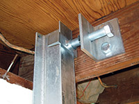 Securing the i-beam system to the top of the floor joist in a foundation wall repair in Smyrna.