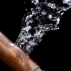 A bursting copper pipe in Huntsville, with water gushing out.